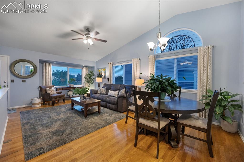 Image 4: Dining area with wood finished floors, a ceiling fan, high vaulted ceiling, and a chandelier
