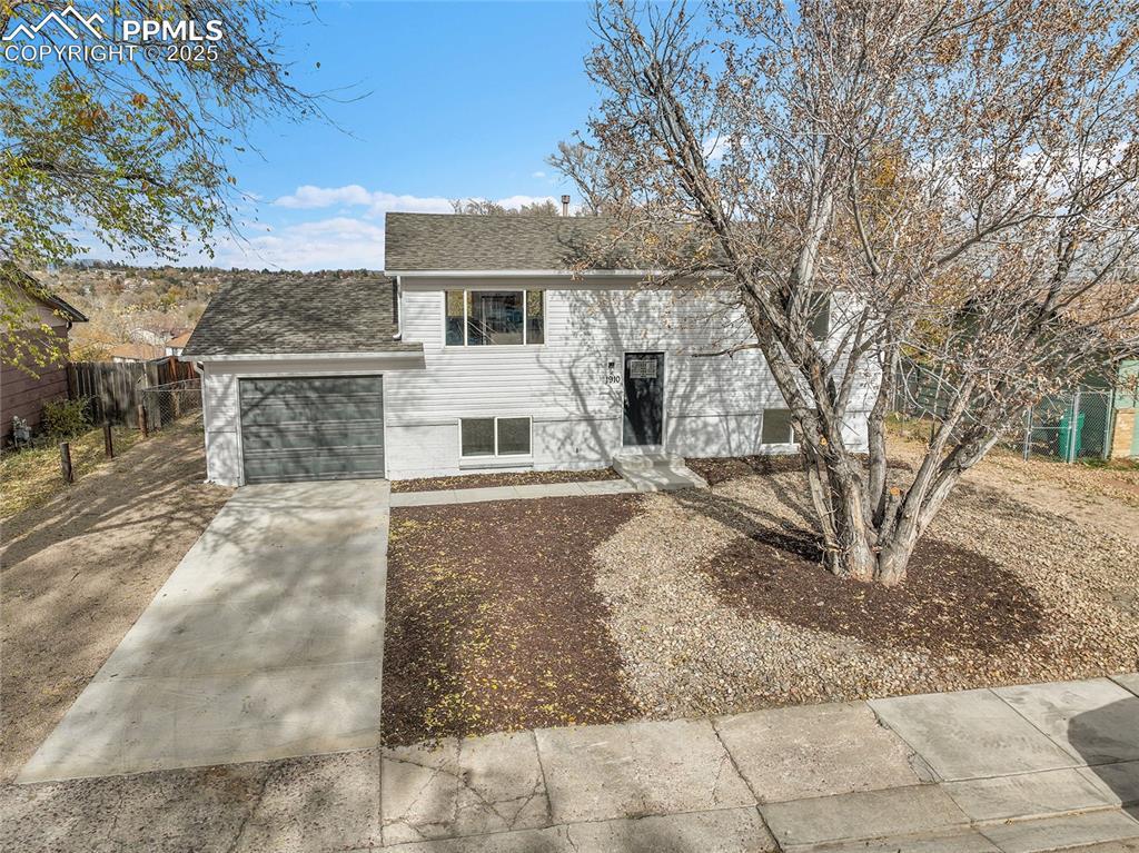 Image 1: Split foyer home featuring driveway, a shingled roof, and a garage