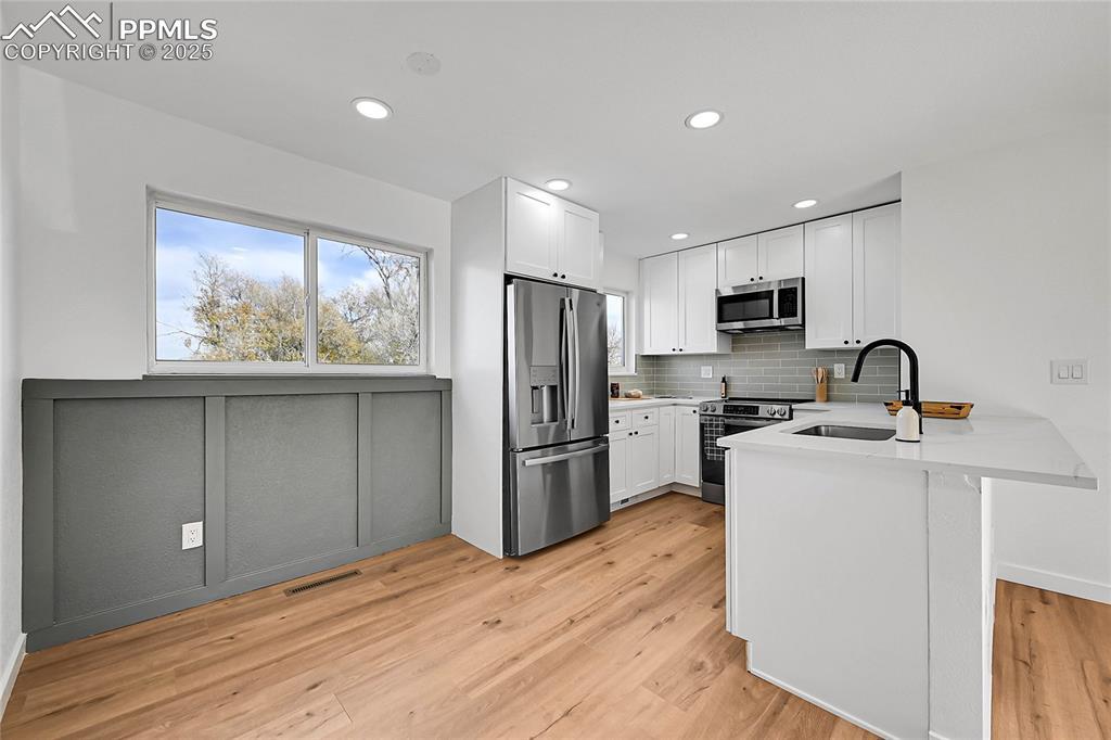 Image 4: Kitchen featuring a peninsula, healthy amount of natural light, stainless steel appliances, white cabinetry, and recessed lighting