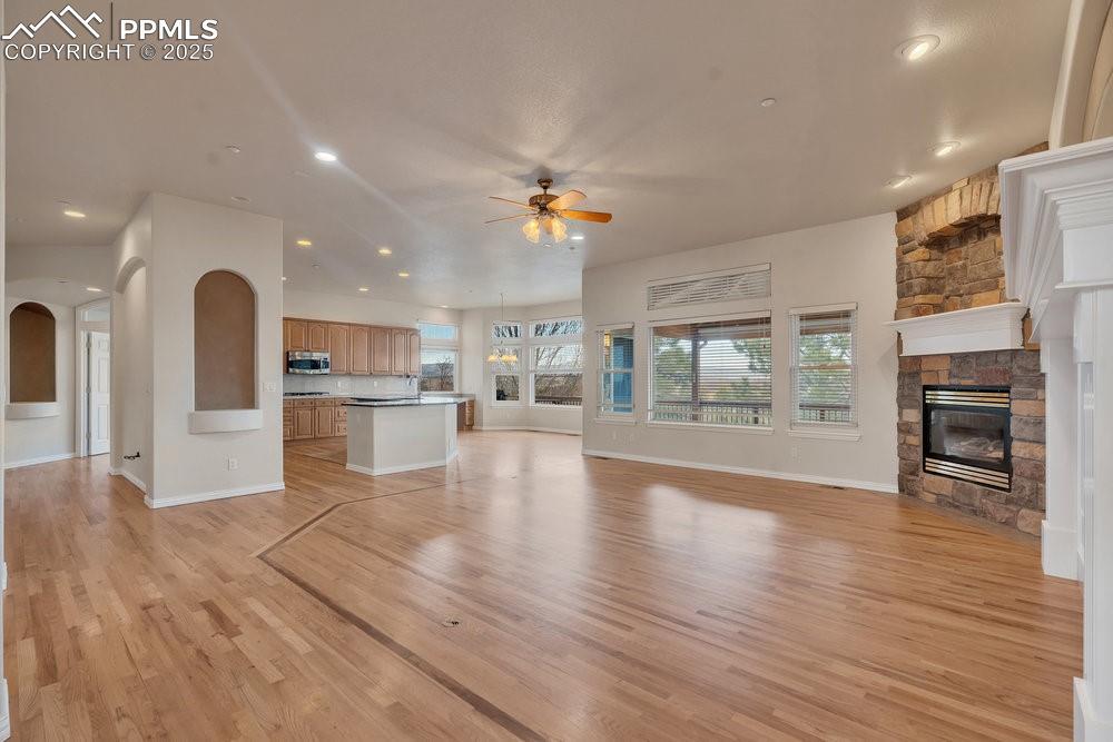 Image 3: Unfurnished living room featuring a ceiling fan, a stone fireplace, light wood finished floors, recessed lighting, and baseboards