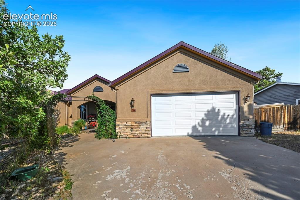 Image 1: Stucco exterior with a peaked roofline, a two-car garage, and stone accent banding