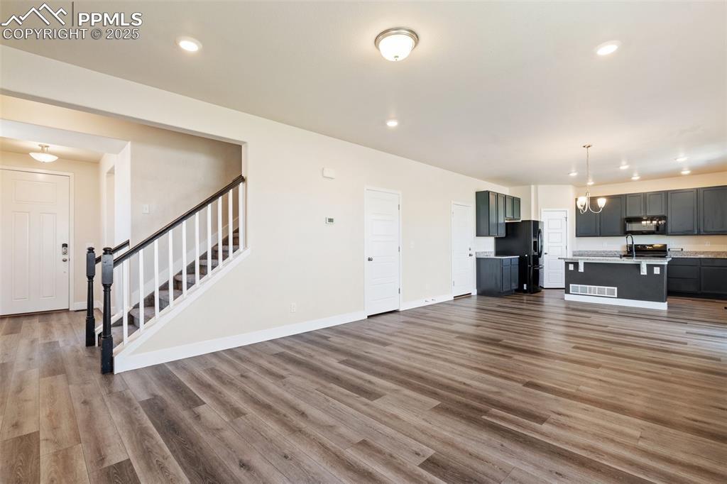Image 4: Unfurnished living room with stairway, wood finished floors, and recessed lighting