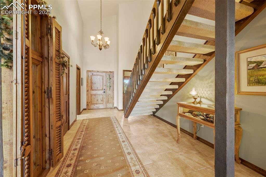 Image 4: Entryway with stairway, a towering ceiling, and a chandelier