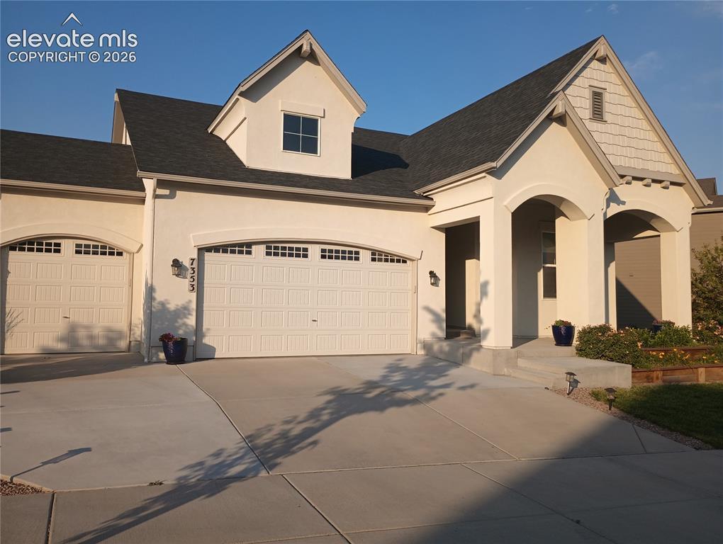 Image 1: Stucco exterior with a prominent arched entry and a shingled gable accent