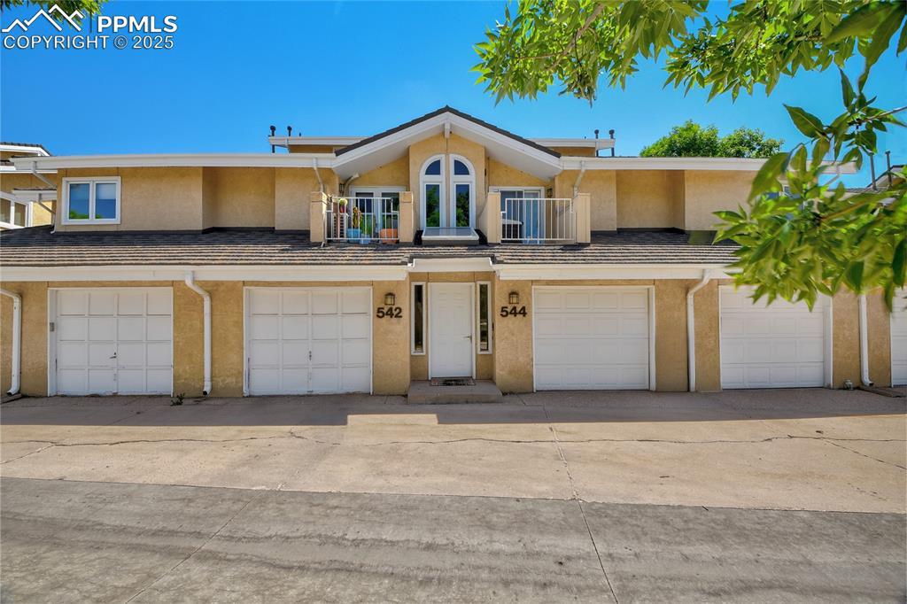 Image 1: Townhome / multi-family property featuring stucco siding, a garage, a balcony, and driveway