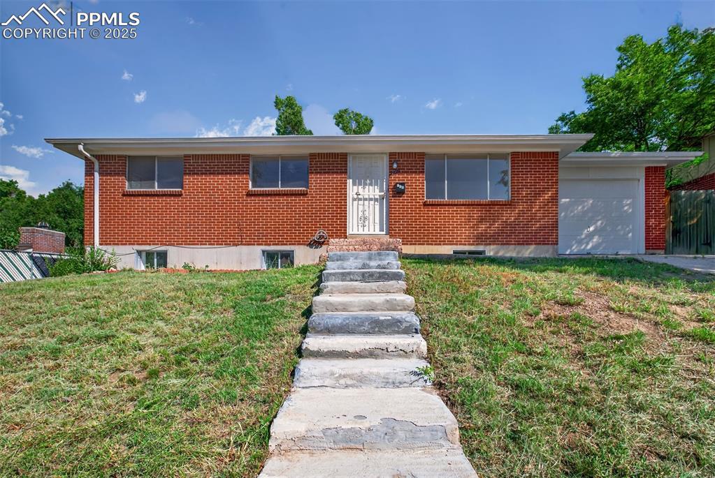 Image 1: Single story home with a front lawn, an attached garage, and brick siding