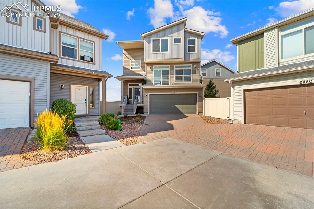 Image 1: View of front of property featuring decorative driveway and a garage