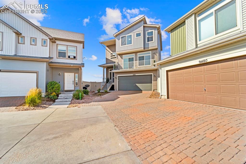 Image 2: View of front of property with decorative driveway, an attached garage, and a residential view