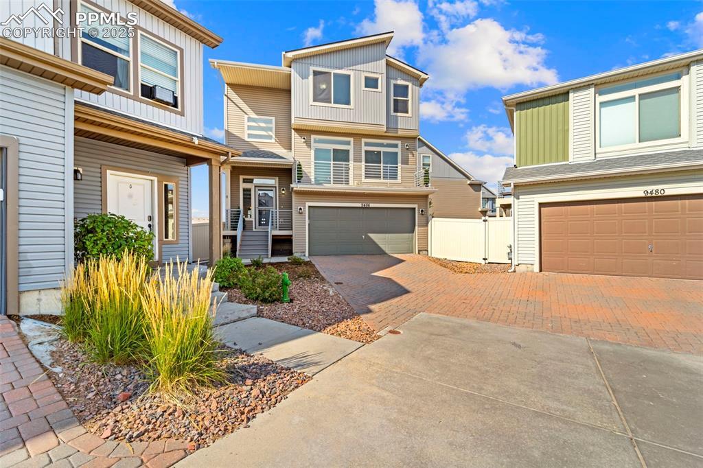 Image 3: View of front facade with decorative driveway, a garage, and a residential view