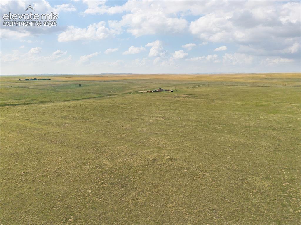 Image 2: Expansive open grassland with a distant structure and scattered trees