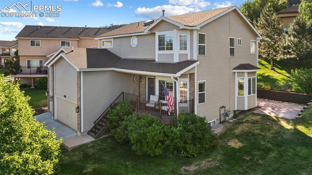 Image 3: View of front of home featuring a front lawn, a shingled roof, a garage, and a patio area