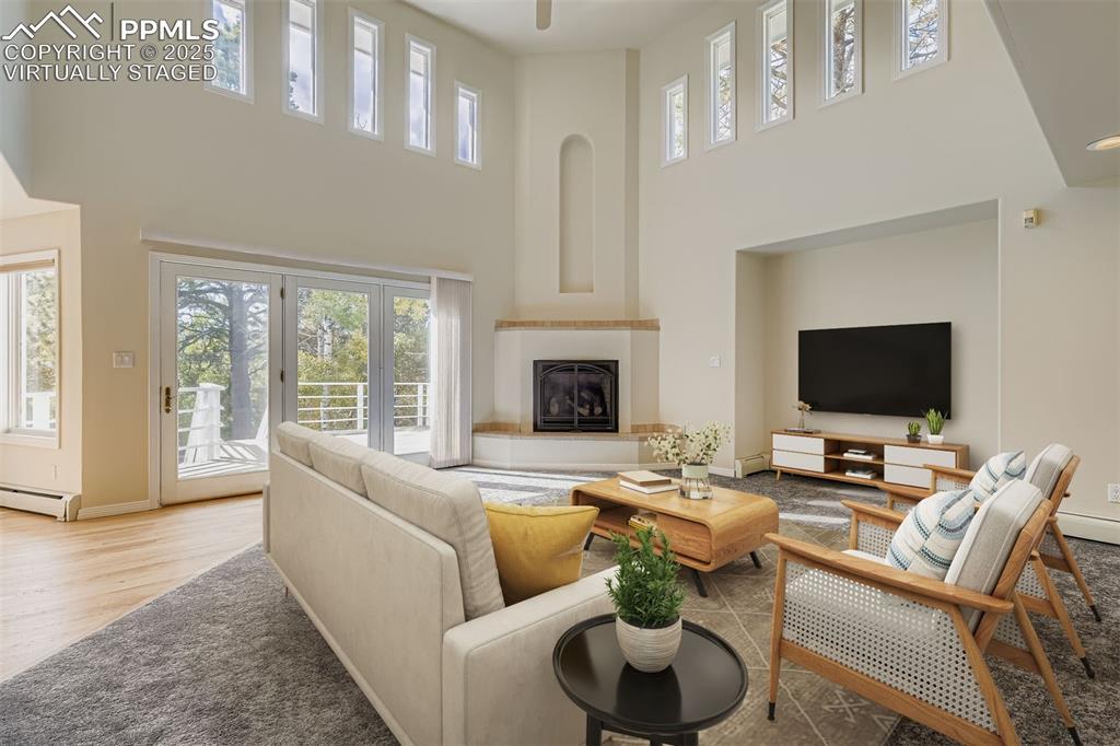 Image 3: Virtually Staged! Living room featuring a towering ceiling, a glass covered fireplace (gas), and baseboard heating (main floor)