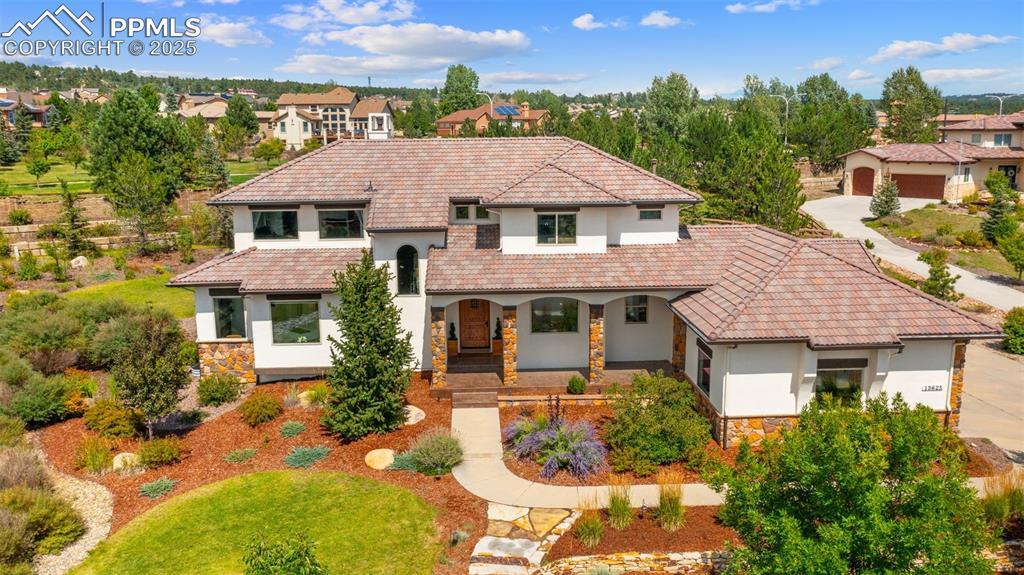 Image 1: Mediterranean / spanish home with stone siding, a porch, stucco siding, and a tiled roof