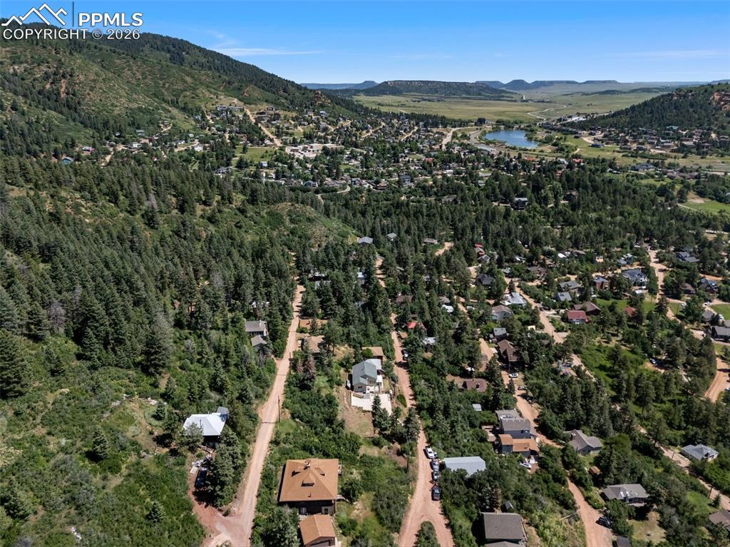 Image 2: Aerial view of property's location featuring a mountain backdrop and a heavily wooded area