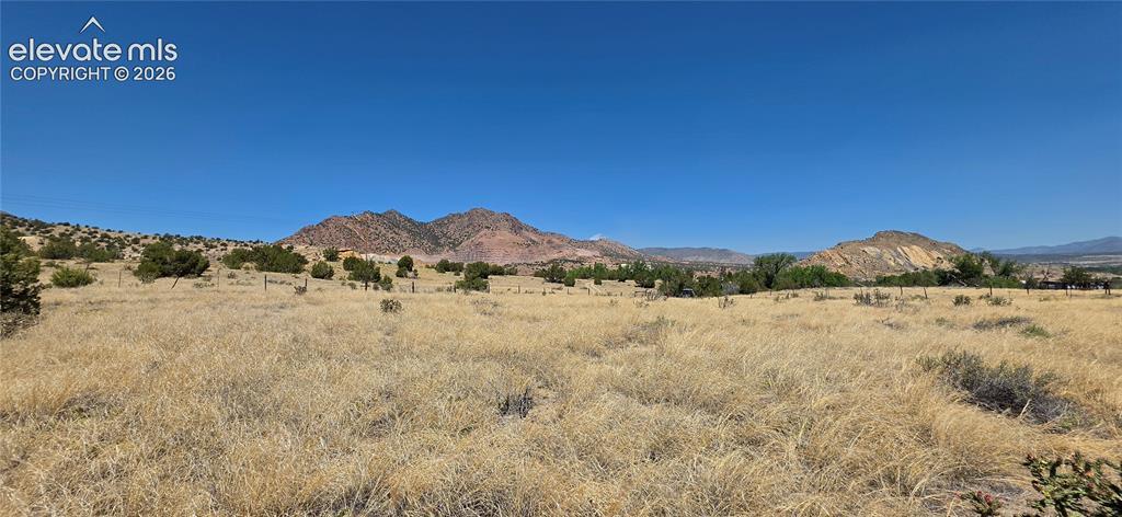 Image 1: Expansive undeveloped land featuring natural terrain and distant mountains under a clear sky