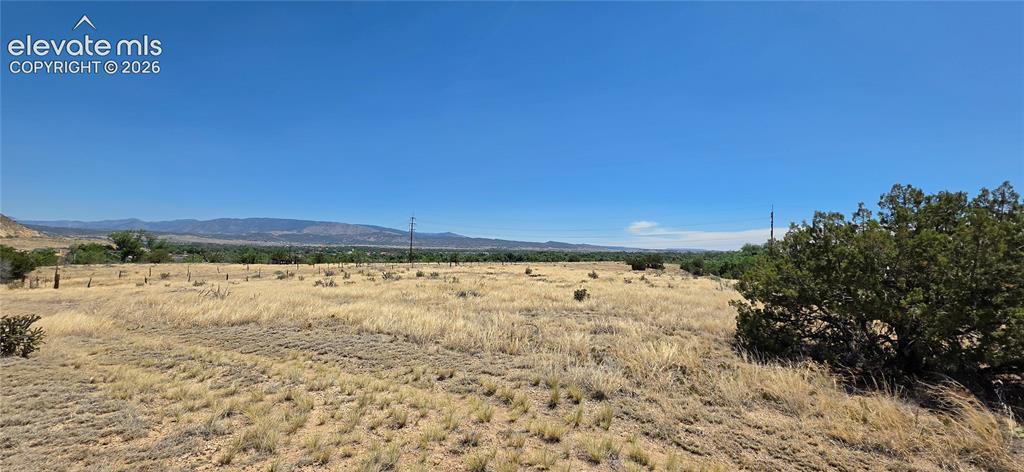 Image 2: Expansive open land featuring natural grasses, scattered brush, and distant mountain ranges under a clear sky