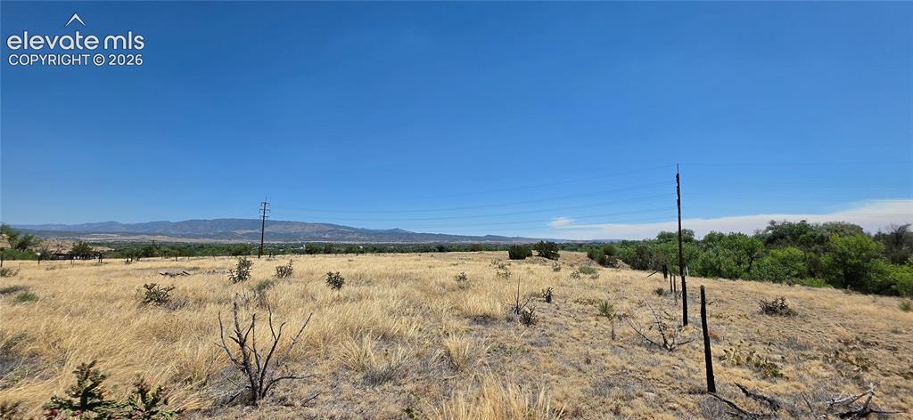 Image 4: Expansive open land featuring a clear blue sky, distant mountains, and varied natural vegetation