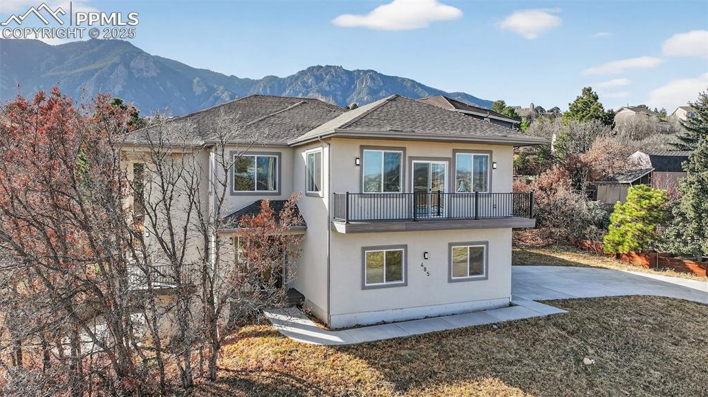 Image 2: Back of property with stucco siding, roof with shingles, a mountain view, a patio area, and a balcony