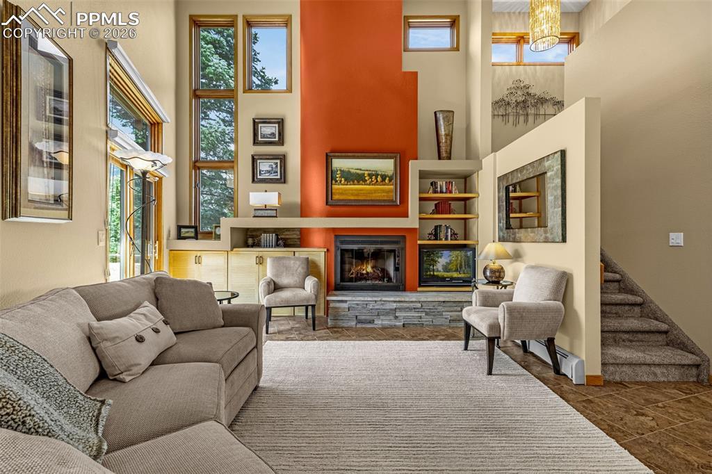 Image 4: Living area featuring a high ceiling and a stone fireplace