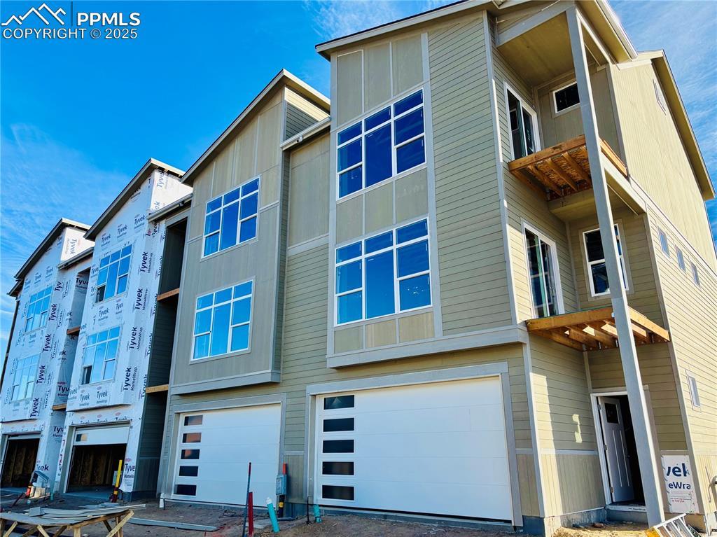 Image 1: Rear view of property featuring a garage