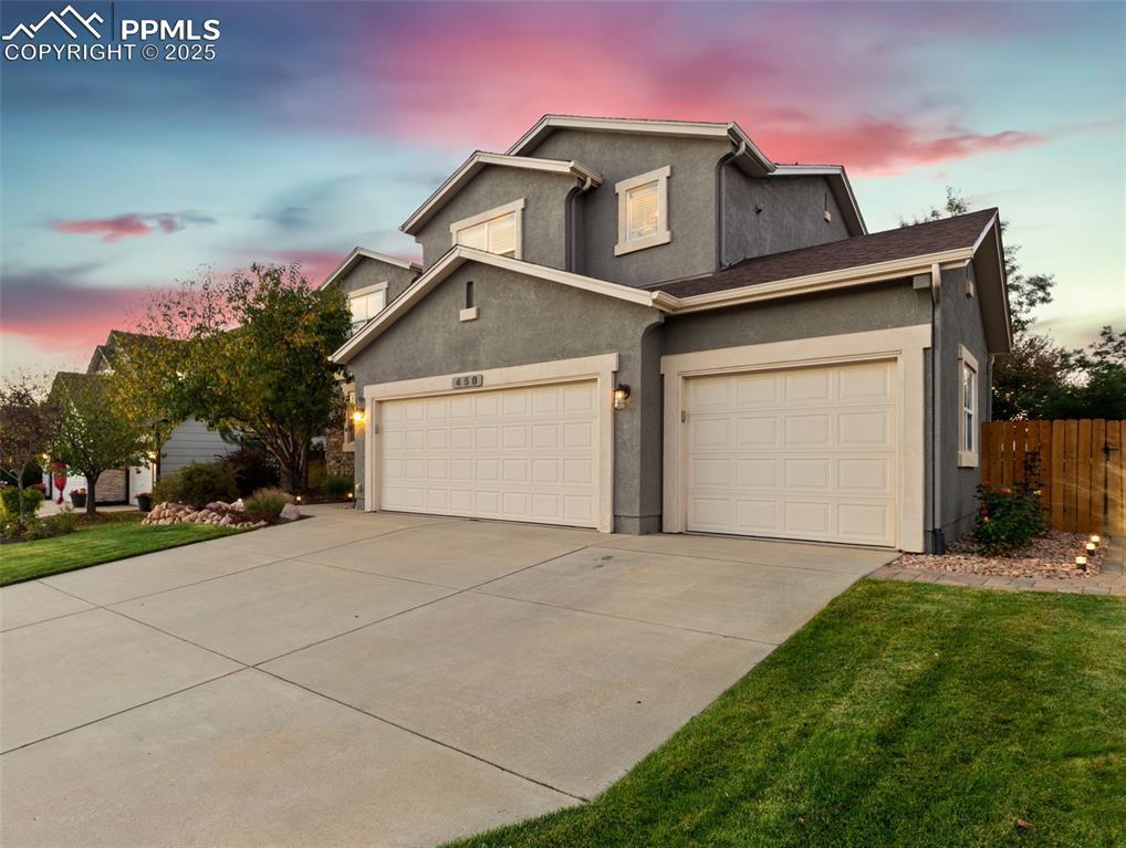 Image 1: Traditional home with driveway, stucco siding, and an attached garage