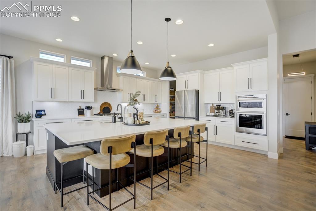Image 4: Gourmet kitchen with upgraded appliances, quartz counters, beverage fridge, upgraded cabinetry, massive island, spacious pantry, gas cooktop, and built in microwave/airfryer