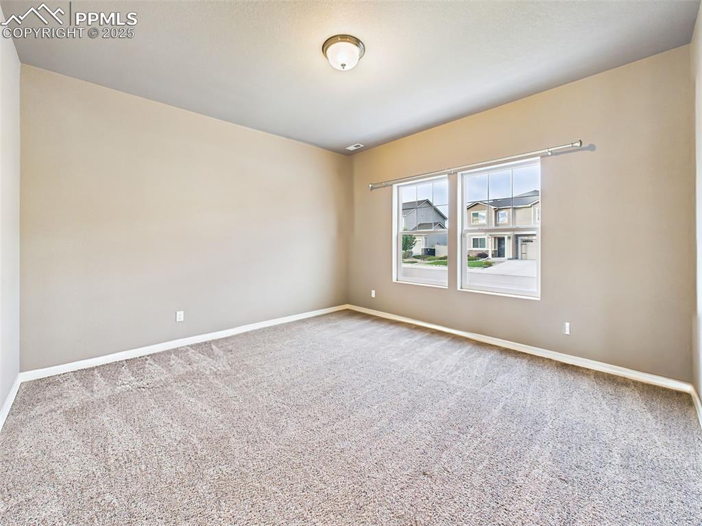 Image 3: Versatile space with large windows and plush carpet, ideal for a home office, formal living area, or playroom.