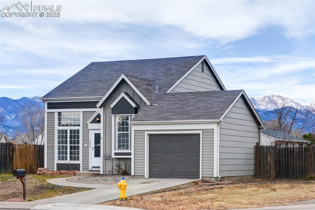 Image 1: View of front of property featuring a mountain view, a garage, concrete driveway, and roof with shingles