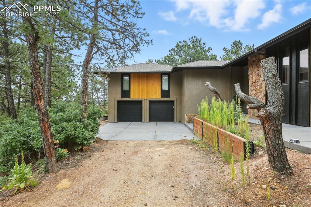 Image 2: View of front of home with stone siding, driveway, a garage, stucco siding, and roof with shingles