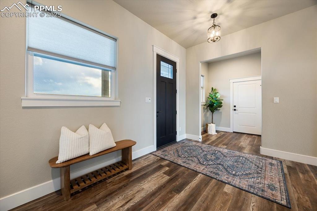 Image 4: Foyer entrance featuring baseboards, wood finished floors, and an inviting chandelier
