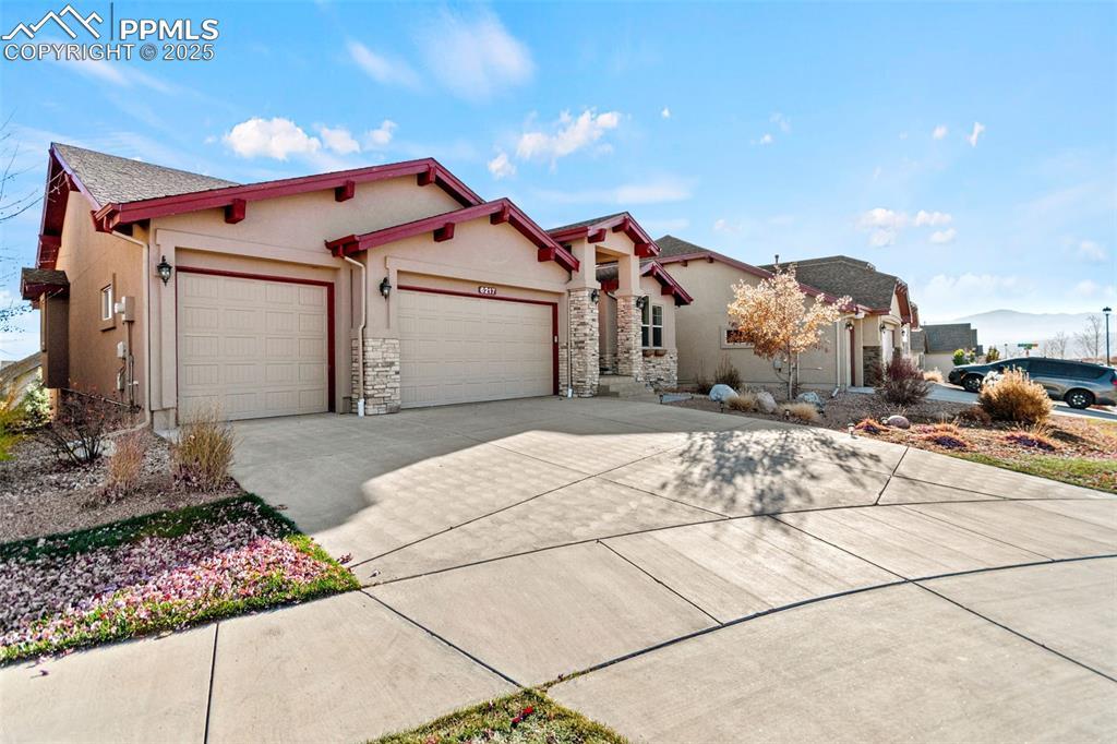 Image 2: View of front facade featuring stucco siding, concrete driveway, an attached garage, and stone siding