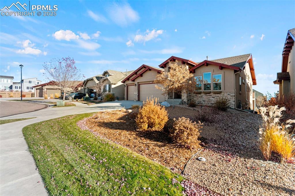 Image 3: View of front of house with stucco siding, stone siding, concrete driveway, a garage, and a residential view