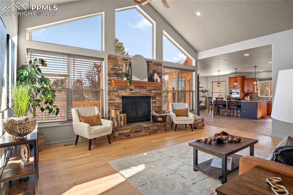 Image 3: Living room with light wood-style flooring, a fireplace, recessed lighting, a high ceiling, and ceiling fan