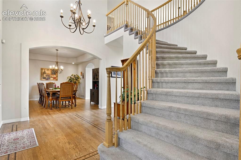 Image 4: Sweeping staircase in vaulted hardwood foyer, with arched entry to...