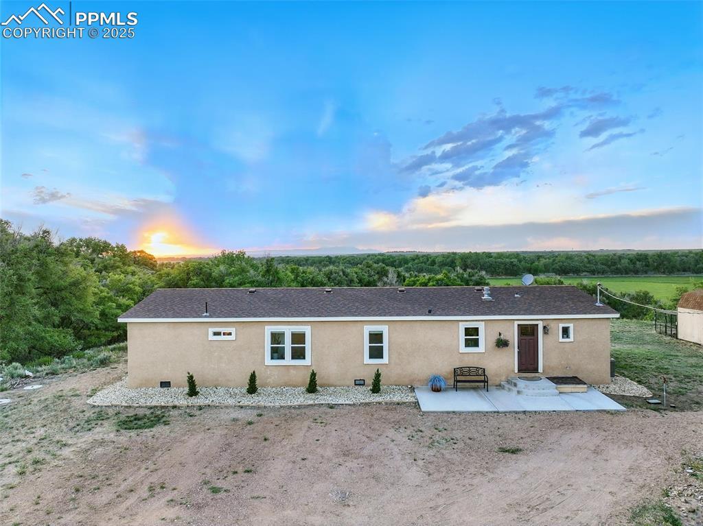 Image 2: Front of house at dusk featuring a patio and stucco siding