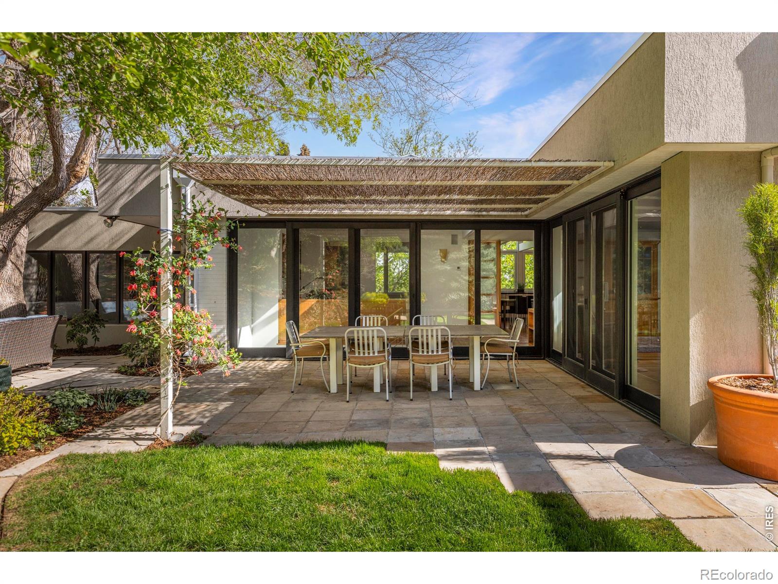 Image 3: The yard unfolds across expansive stone patios, grassy lawn, and terraced garden beds, with the Flatirons framed in full view above. Image 3: The yard unfolds across expansive stone patios, grassy lawn, and terraced garden beds, with the Flatirons framed in full view above.