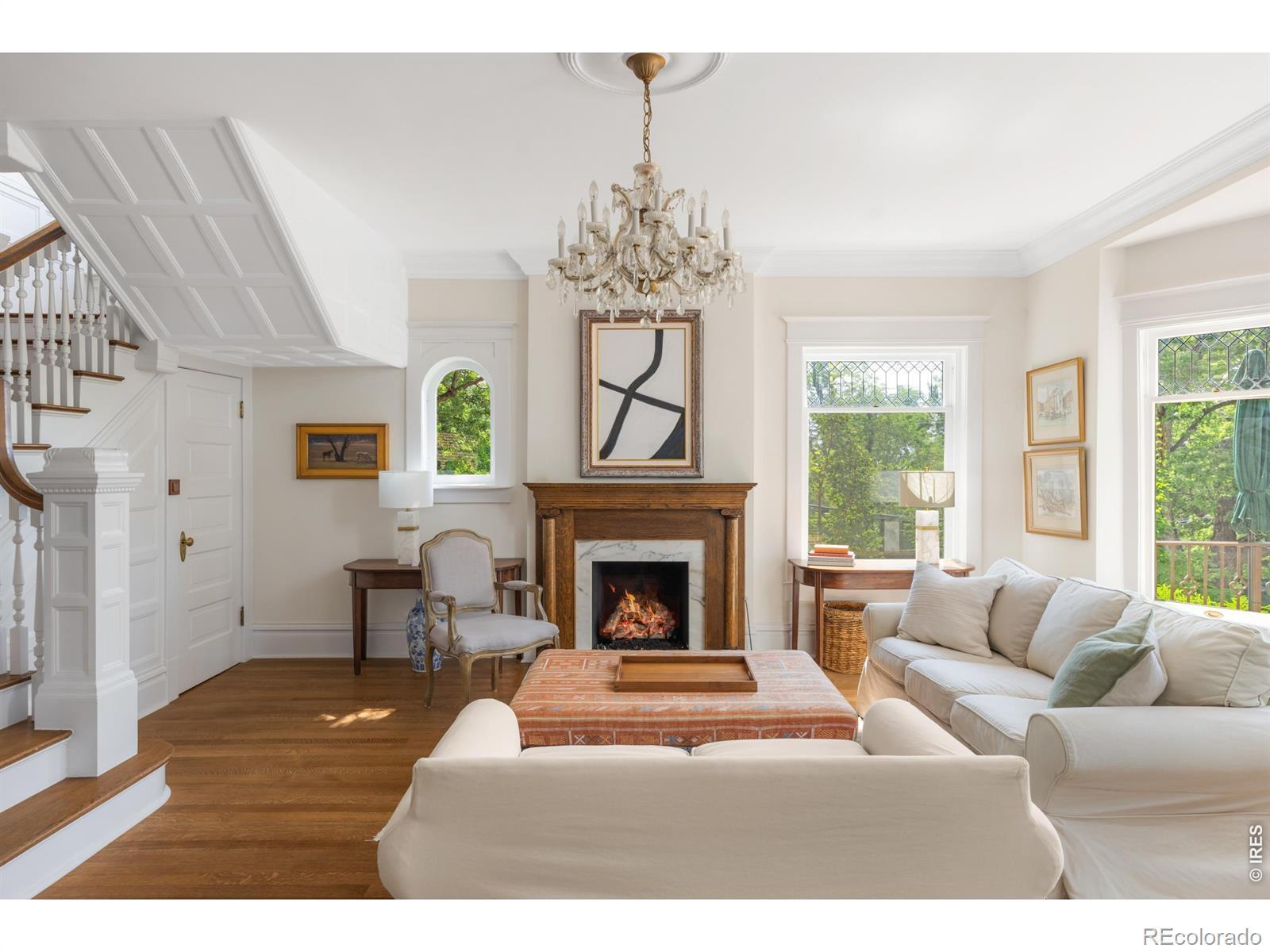 Image 4: The living room welcomes you with restored hardwood floors, original millwork, oversized leaded glass windows, and a fireplace that reflects the craftsmanship of the homes 1903 origins. Image 4: The living room welcomes you with restored hardwood floors, original millwork, oversized leaded glass windows, and a fireplace that reflects the craftsmanship of the homes 1903 origins.