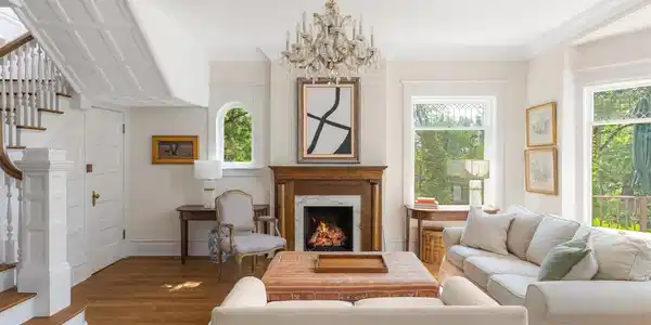 Image 4: The living room welcomes you with restored hardwood floors, original millwork, oversized leaded glass windows, and a fireplace that reflects the craftsmanship of the homes 1903 origins. Image 4: The living room welcomes you with restored hardwood floors, original millwork, oversized leaded glass windows, and a fireplace that reflects the craftsmanship of the homes 1903 origins.