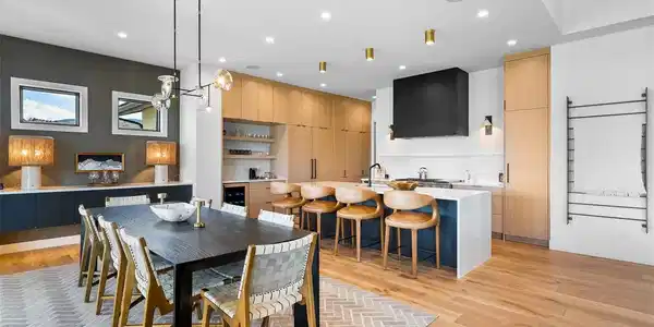 Image 3: Open-concept dining anchored by custom cabinetry and a quartz waterfall island.