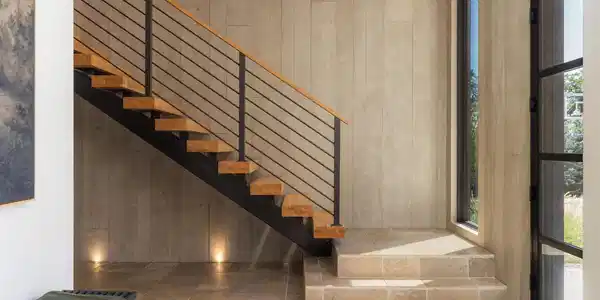 Image 4: A floating staircase rises alongside a dramatic two-story wall of board-formed concrete, one of the homes defining architectural elements. Image 4: A floating staircase rises alongside a dramatic two-story wall of board-formed concrete, one of the homes defining architectural elements.
