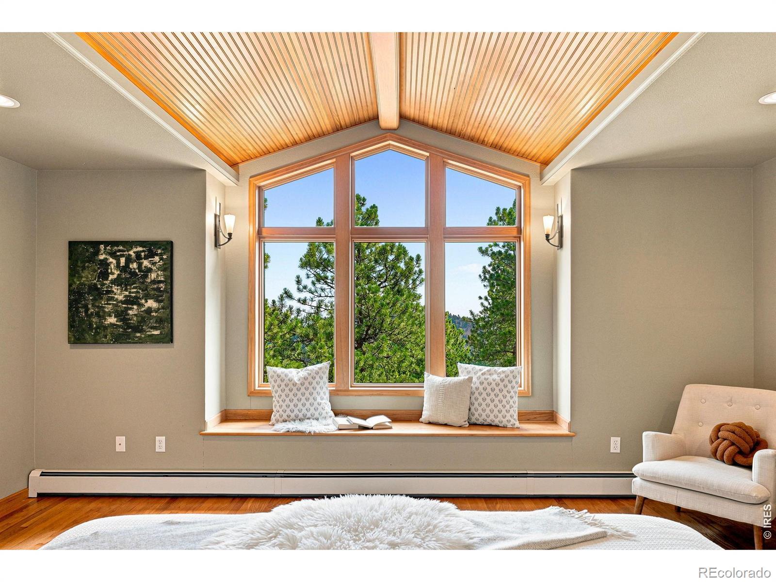 Image 2: Primary bedroom on the entry level with vaulted wood ceilings, intentional lighting, treetop views and serenity.
