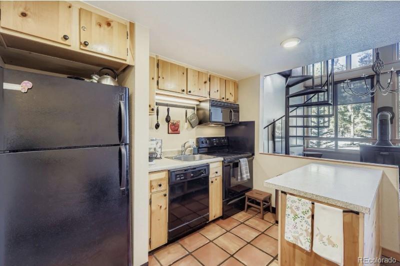 Image 4: Kitchen with fridge, microwave, dishwasher and electric range. Island has open shelving for additional storage.