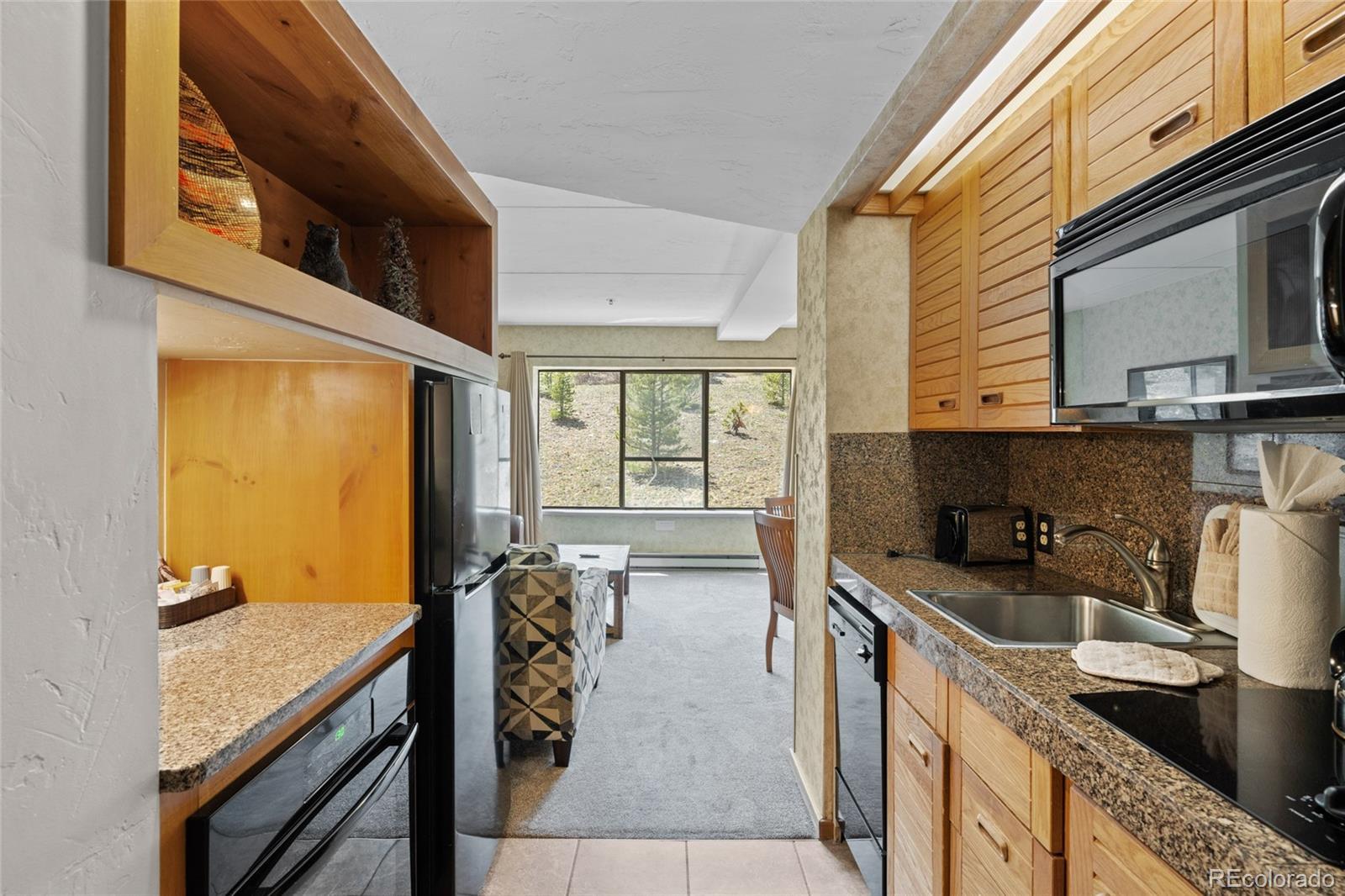 Image 2: Kitchen with black appliances, a sink, light tile patterned floors, light carpet.