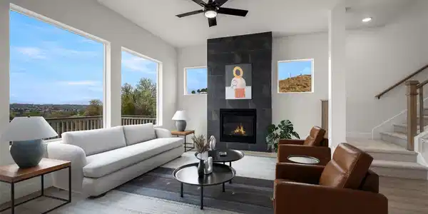 Image 2: Virtually staged bright living space featuring large picture windows, a modern fireplace with dark tile surround, light wood-finish flooring, and a ceiling fan. Image 2: Virtually staged bright living space featuring large picture windows, a modern fireplace with dark tile surround, light wood-finish flooring, and a ceiling fan.