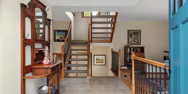 Image 4: The entry opens to a warm, multi-level interior with hardwood floors, natural wood detailing, and an open staircase. Image 4: The entry opens to a warm, multi-level interior with hardwood floors, natural wood detailing, and an open staircase.
