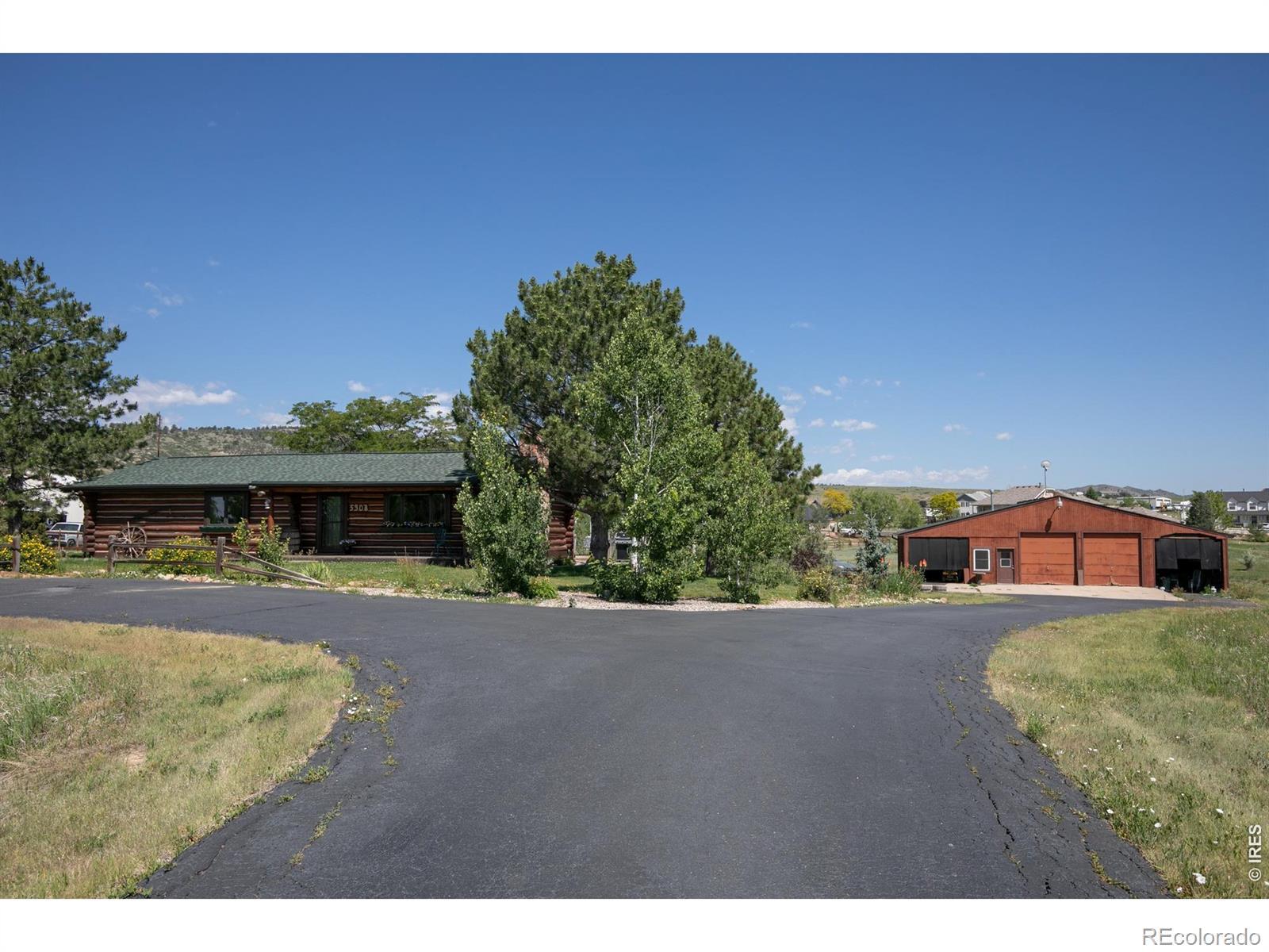 Image 2: Welcoming front approach with paved driveway, mature trees, and a beautiful view of the custom log home and detached garage/workshop. Image 2: Welcoming front approach with paved driveway, mature trees, and a beautiful view of the custom log home and detached garage/workshop.