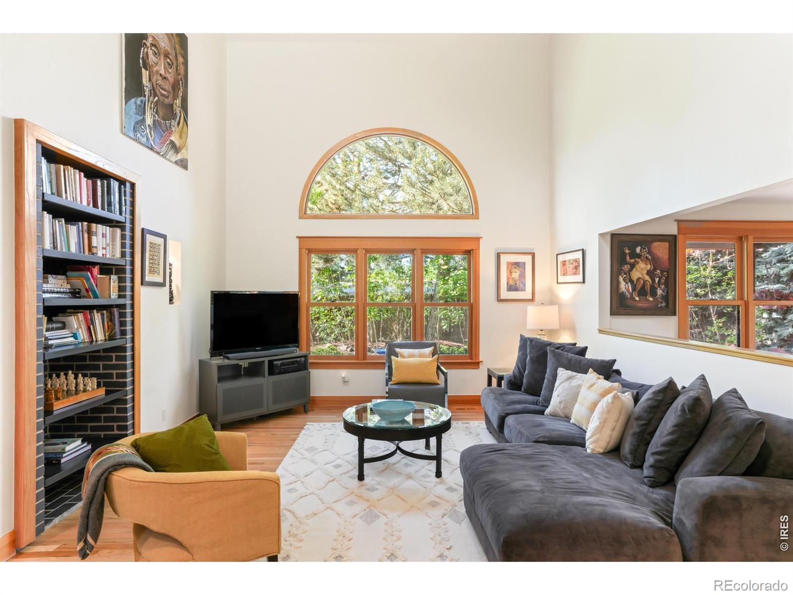 Image 4: The main level living room offers a double-height vaulted ceiling and large picture windows with private, treed views to the back yard and garden. Image 4: The main level living room offers a double-height vaulted ceiling and large picture windows with private, treed views to the back yard and garden.