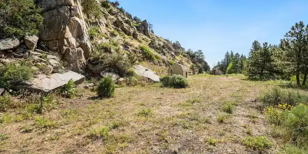 Image 2: Looking E across buildable acre with lots of rock outcroppings.