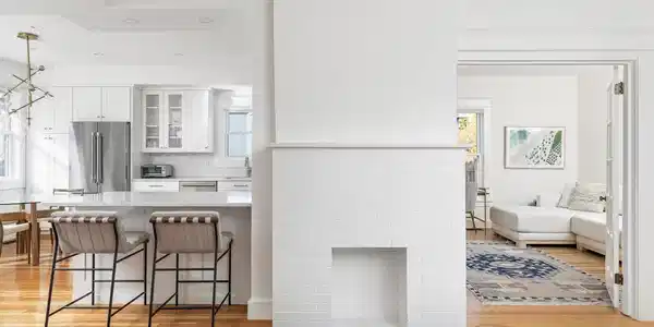 Image 3: Gleaming wood floors and a crisp, modern palette create an inviting flow between the kitchen and living room.