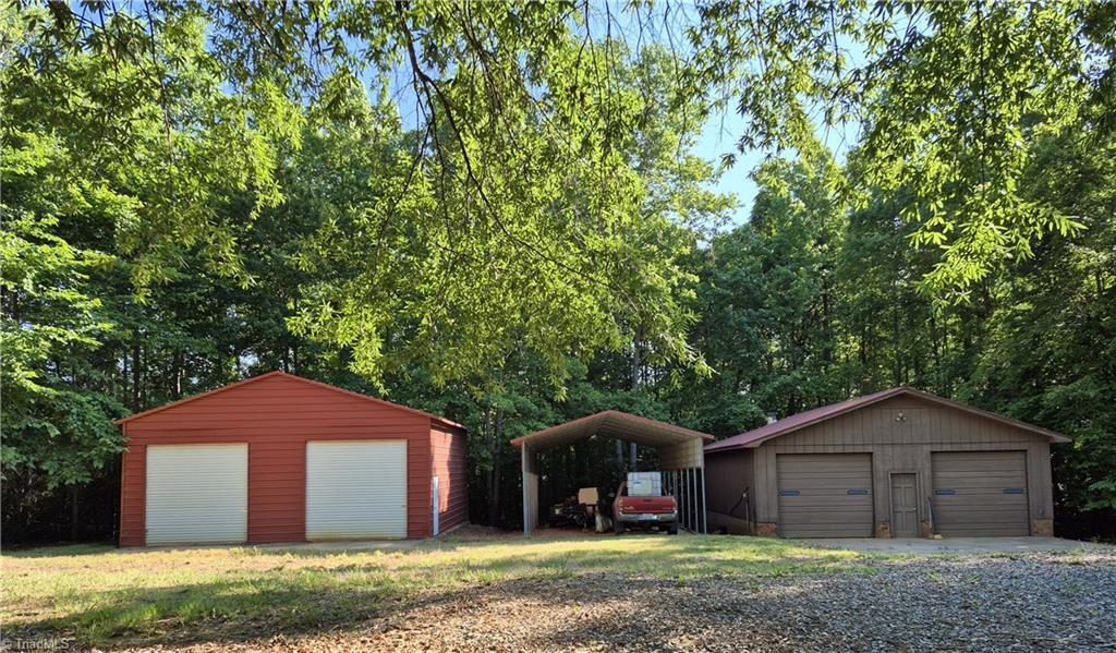 Image 4: Steel garage with side entrance, detached carport, workshop with woodburning stove and bathroom.